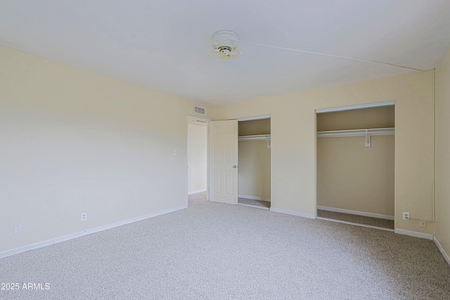 unfurnished bedroom featuring carpet, visible vents, baseboards, and two closets