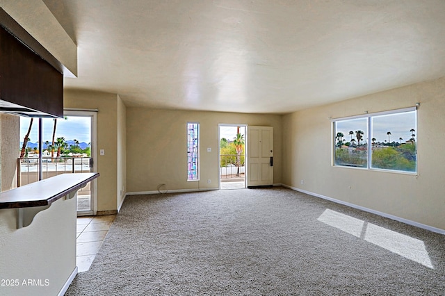 empty room featuring baseboards, a healthy amount of sunlight, and light colored carpet