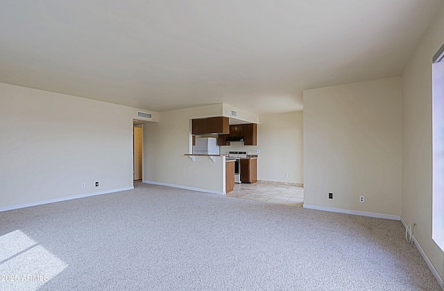 unfurnished living room featuring baseboards, visible vents, and light colored carpet