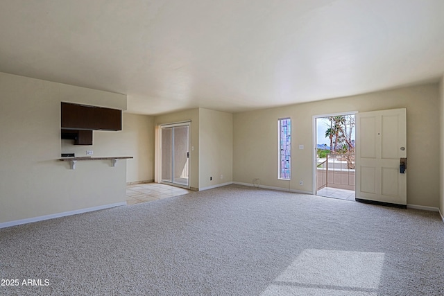 unfurnished living room featuring light carpet and baseboards