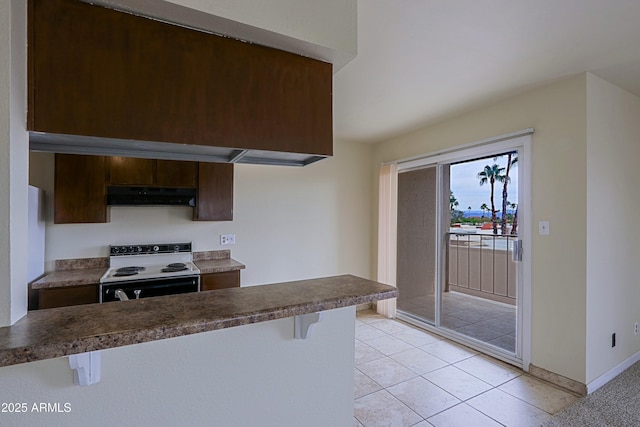 kitchen featuring range with electric cooktop, dark countertops, a kitchen bar, and under cabinet range hood