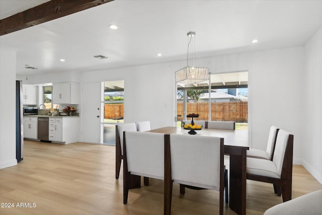 dining room with sink, a healthy amount of sunlight, beamed ceiling, and light hardwood / wood-style flooring