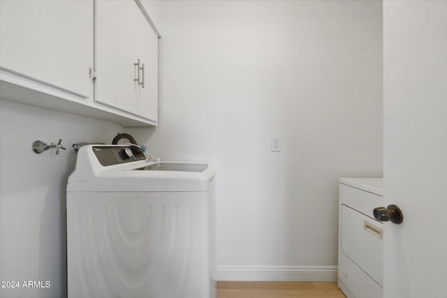 washroom with light hardwood / wood-style flooring, washing machine and clothes dryer, and cabinets