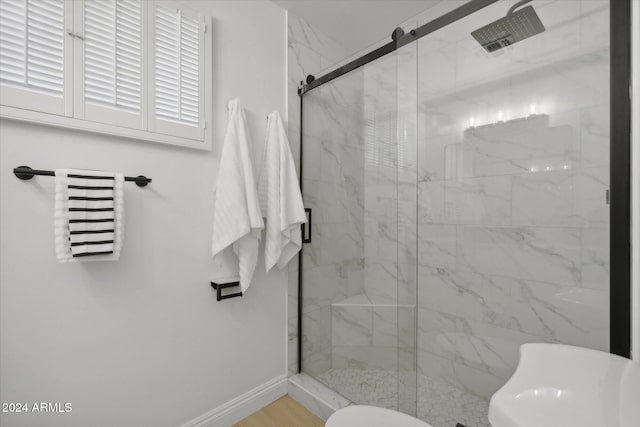 bathroom featuring a shower with shower door and toilet