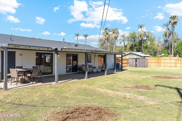 back of property with a storage shed, cooling unit, a patio, and a lawn