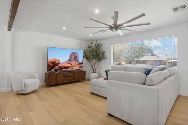 living room featuring beam ceiling, light wood-type flooring, and ceiling fan