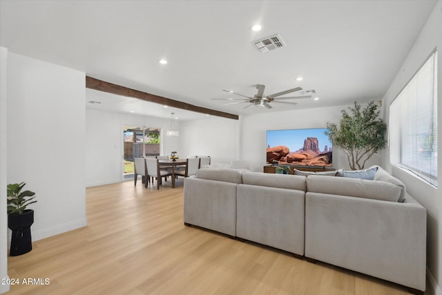 living room with ceiling fan, beamed ceiling, and light wood-type flooring