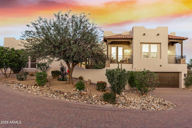 view of front of house featuring a garage, stucco siding, a tile roof, and decorative driveway
