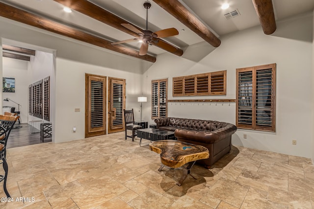 living room featuring a towering ceiling, beamed ceiling, and ceiling fan