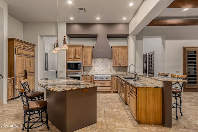 kitchen with visible vents, stone countertops, a kitchen bar, a sink, and stainless steel appliances