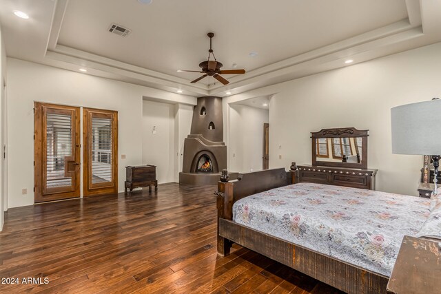 bedroom featuring access to outside, ceiling fan, a tray ceiling, and dark hardwood / wood-style flooring