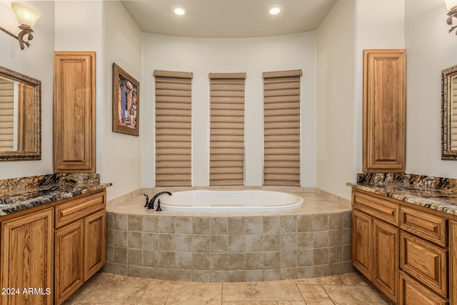 bathroom featuring vanity, a relaxing tiled tub, and tile patterned floors