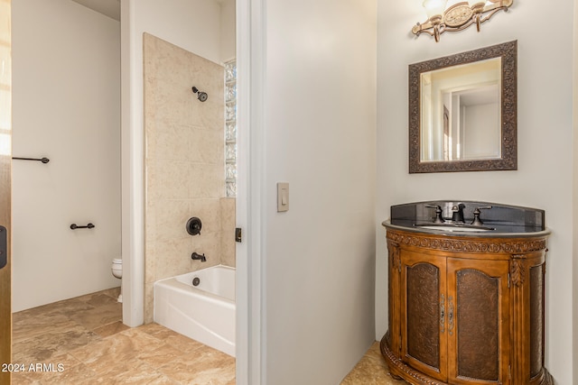 full bathroom with tiled shower / bath, vanity, and toilet