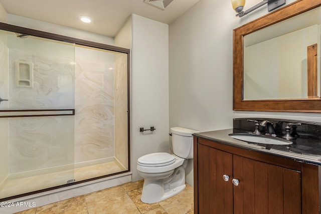 bathroom featuring toilet, vanity, and a shower with door