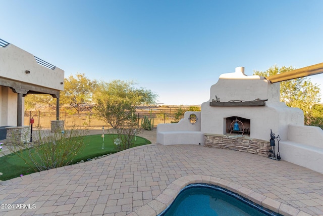 view of pool featuring a fenced backyard, a fenced in pool, exterior fireplace, and a patio area