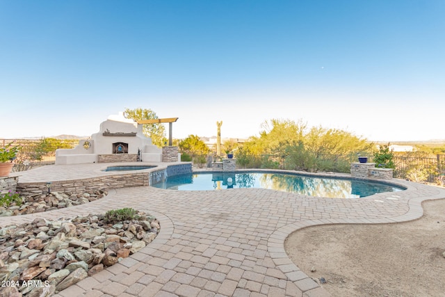 view of swimming pool featuring an outdoor fireplace and a patio