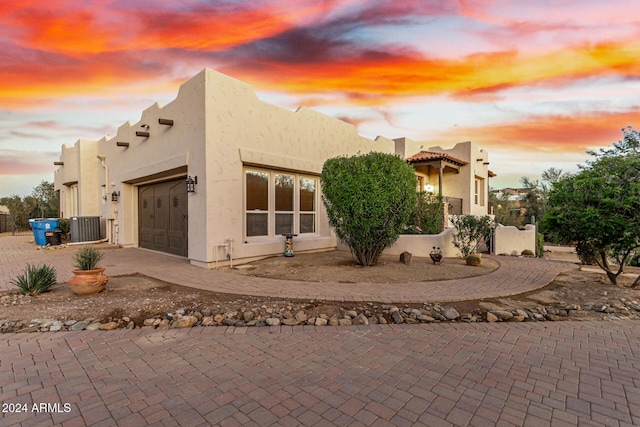 view of front of property with a garage, central AC unit, stucco siding, and decorative driveway