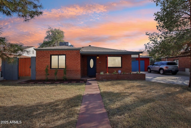 bungalow-style house with brick siding, fence, and a front yard