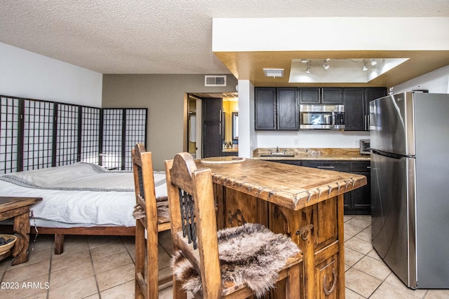 kitchen with light tile patterned floors, stainless steel appliances, butcher block counters, and visible vents