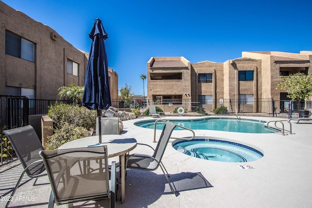 pool with a patio area, fence, and a community hot tub