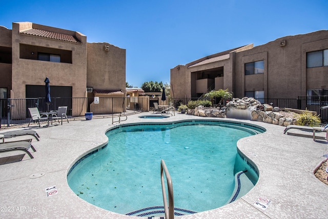 pool with a community hot tub, a patio area, and fence