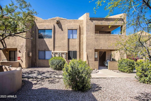 rear view of house featuring stucco siding