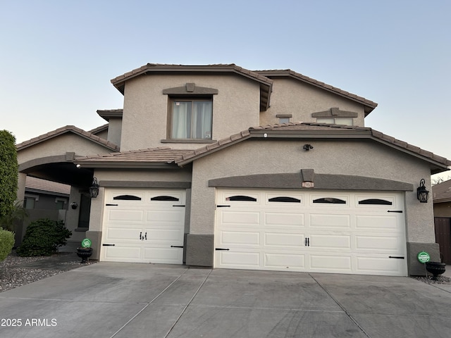 traditional-style house with stucco siding, concrete driveway, and a tile roof