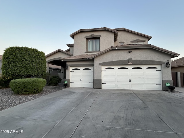 traditional home featuring stucco siding, an attached garage, driveway, and a tiled roof