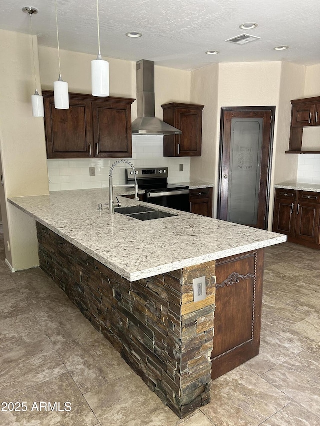 kitchen with tasteful backsplash, visible vents, wall chimney range hood, stainless steel electric range oven, and a sink