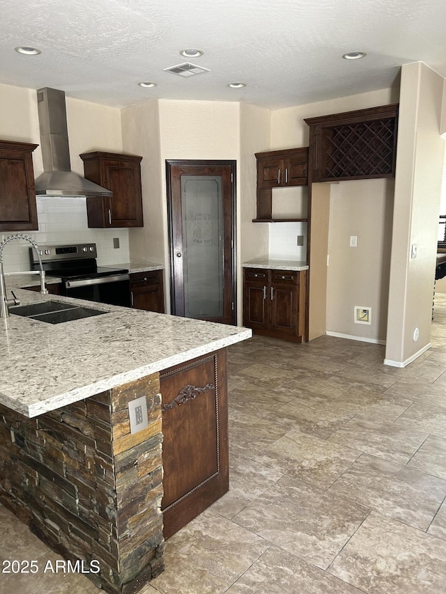 kitchen with decorative backsplash, wall chimney range hood, stainless steel electric stove, and visible vents