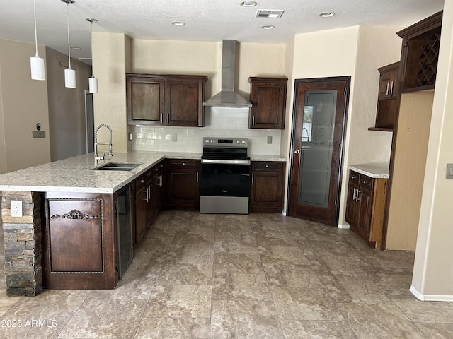 kitchen with visible vents, wall chimney range hood, decorative backsplash, electric range, and a sink