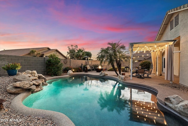 pool at dusk featuring a pergola and a patio area