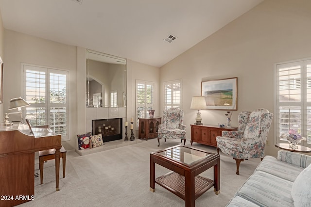 carpeted living room featuring a fireplace, high vaulted ceiling, and a wealth of natural light