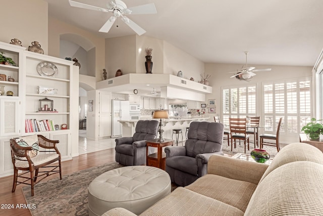 living room featuring ceiling fan, light hardwood / wood-style floors, and vaulted ceiling