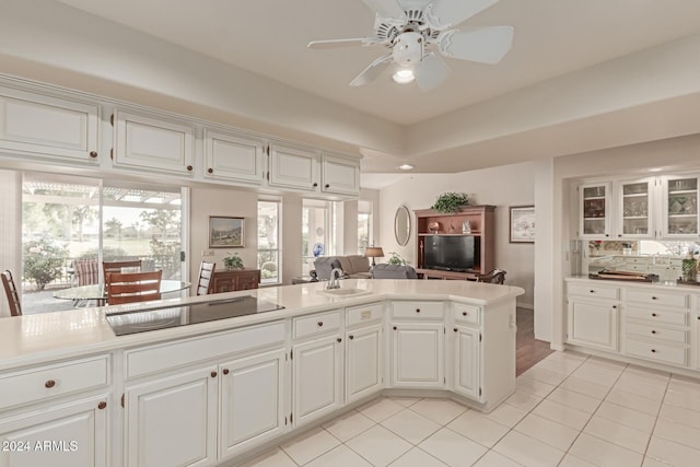 kitchen with black electric stovetop, plenty of natural light, ceiling fan, and white cabinets