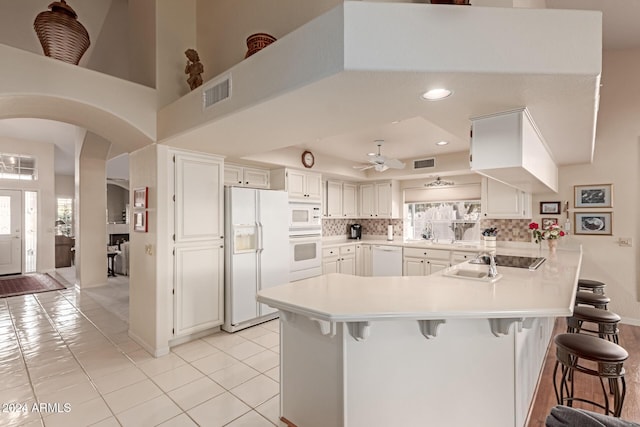 kitchen featuring white cabinets, a breakfast bar, ceiling fan, and white appliances