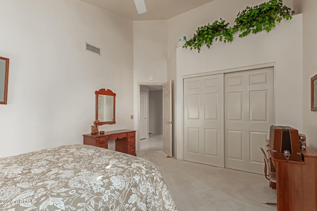 bedroom with light carpet, a closet, ceiling fan, and a high ceiling