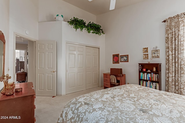 bedroom with a towering ceiling, light carpet, a closet, and ceiling fan