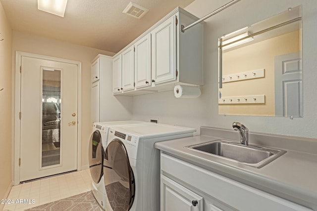 laundry area with washing machine and clothes dryer, sink, and cabinets