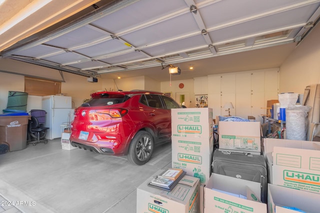 garage featuring white refrigerator and a garage door opener