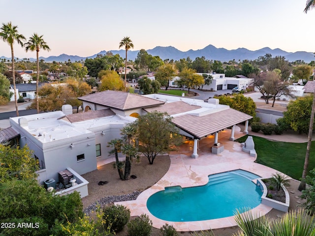 pool at dusk featuring a mountain view and a patio area