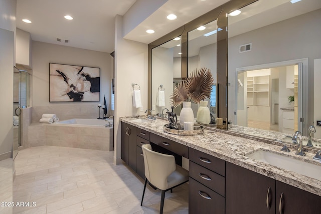 bathroom with vanity, tiled bath, and tile patterned flooring