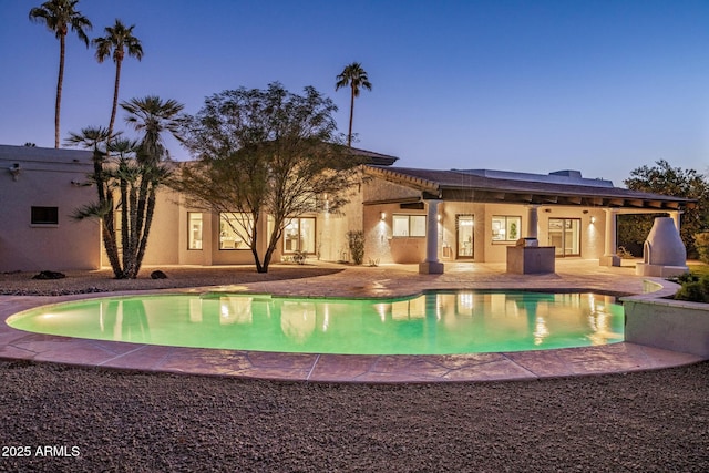 pool at dusk featuring a patio