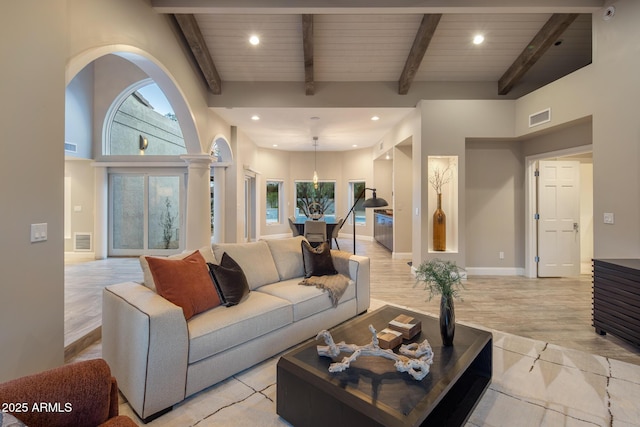 living room with beam ceiling, wood ceiling, light hardwood / wood-style flooring, and a high ceiling