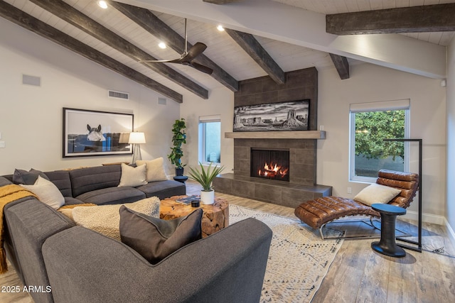 living room with a tiled fireplace, vaulted ceiling with beams, hardwood / wood-style floors, and wooden ceiling