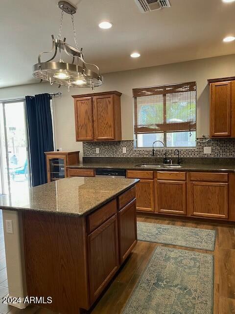 kitchen featuring a center island, backsplash, dark wood-type flooring, an inviting chandelier, and sink