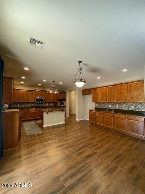 kitchen featuring a kitchen island, decorative light fixtures, dark hardwood / wood-style floors, and appliances with stainless steel finishes