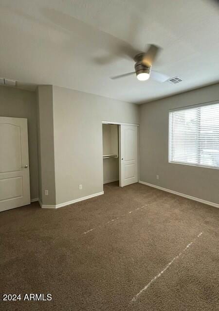 unfurnished bedroom featuring ceiling fan, a closet, and dark colored carpet