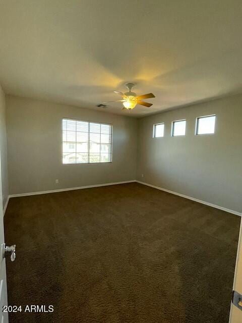 unfurnished room featuring dark carpet and ceiling fan