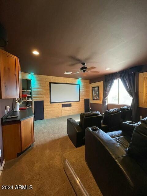 carpeted cinema room featuring ceiling fan and wooden walls